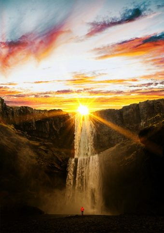 Il sole che tramonta alle spalle di una splendida cascata