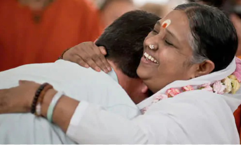 Amma abbraccia una persona, dà il darshan